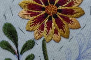 Detalle desde arriba del proceso de bordado a mano de una flor con el patrón