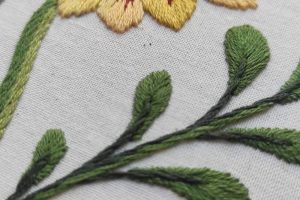 Detalle del bordado botánico de una flor hecho a mano hecho desde un lado