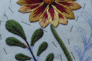 proceso de bordado de una flor y sus hojas, patrón y tela trasera