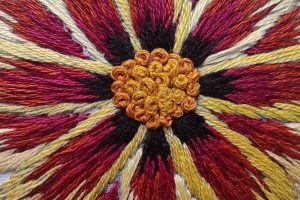 Detalle desde muy cerca del bordado de una flor parecida a un girasol y sus estambres